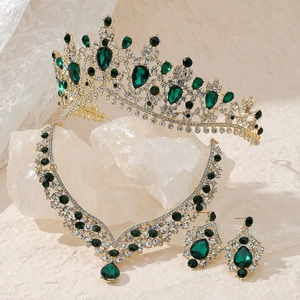 Lussuoso set di gioielli d'oro con cristalli verdi e diamanti su espositore in pietra