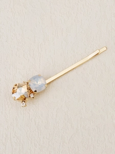 Close-up of golden hair clip with amber gemstone and blue opal faceted stones