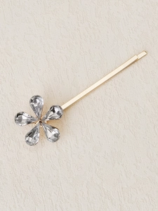 Macro detail of a golden flower hair clip with sparkling crystal petals for kids