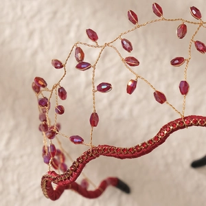 Macro detail of handmade woven velvet headband with sparkling red crystals and gold wire