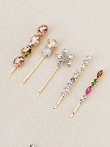 Detail of five gold hair pins with colorful rhinestones in champagne and pink tones