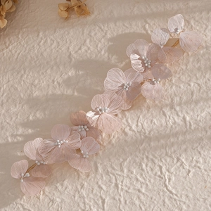 Elegant pink floral bridal headband with gold wires and pearls on beige textured paper