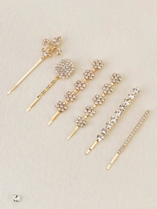 Detailed view of six gold-toned rhinestone hair pins in floral and geometric shapes