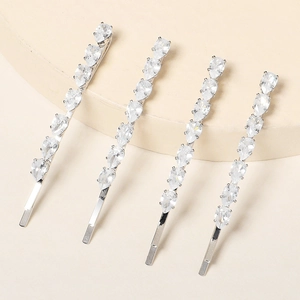 Close-up of four silver hair clips with pear-shaped zircon stones in a linear arrangement