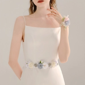 Detail of floral bridal sash and wrist corsage with blue fabric flowers and pearls
