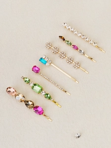Detailed view of seven gold bobby pins set with colorful rhinestones and pearls