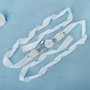 Detail of bridal sash with white handmade flowers and sequins on a silky ribbon