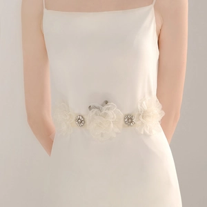Close-up of handmade organza flowers and vintage silver rhinestones on bridal satin belt