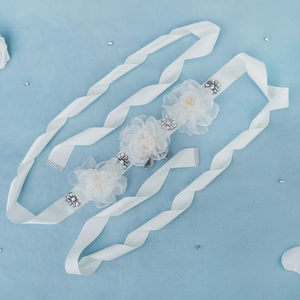 Detail of bridal sash featuring white 3D mesh flowers with silver rhinestones and satin ribbon
