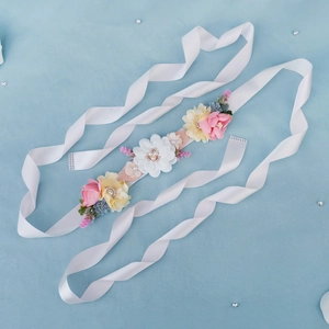 Detailed macro view of bridal sash featuring handmade pink and beige flowers with pearls