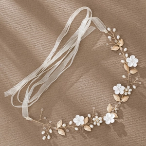 Detail of bridal headband with white ceramic flowers, gold leaves, and organza ribbons