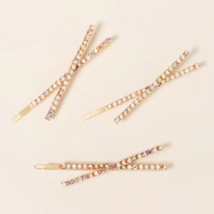 Detail view of 3-piece set of gold X-shaped hair clips with rainbow rhinestones