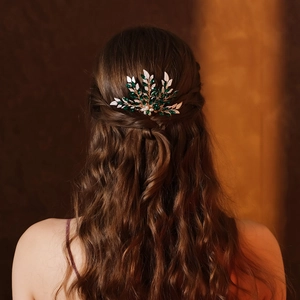 Dettaglio di un pettine da sposa vintage con strass verdi su capelli castani mossi