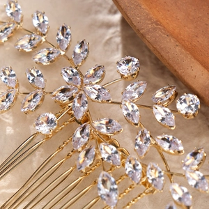 Dettaglio macro del pettine da sposa con zirconi scintillanti e petali in lega dorata