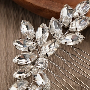 Elegant silver bridal hair comb with leaf-shaped crystals on a rustic wooden background