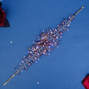 Detailaufnahme des handgefertigten Brauthaarschmucks mit lila Kristallen und Golddraht
