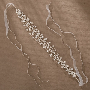 Détail d'un serre-tête en perles multicouches avec des rubans en organza sur fond texturé