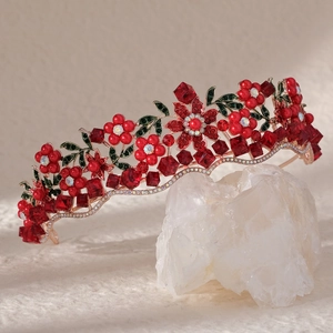 Close-up of red crystals and enamel leaves on a vintage gold bridal crown