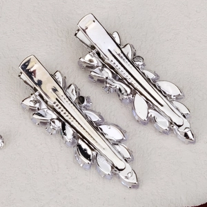Détail de barrettes argentées avec des strass de forme marquise et une pince bec de canard