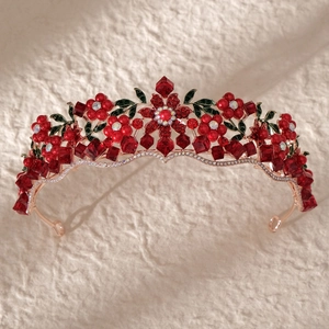 Close-up of vintage bridal crown with red crystal flowers and rose gold finish