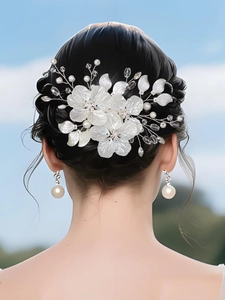 Détail d'une mariée portant des pinces à cheveux à fleurs blanches et des boucles d'oreilles