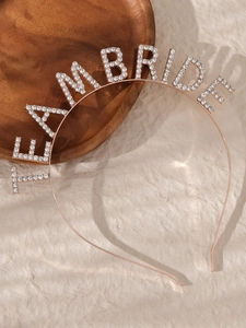 Detail of rose gold Team Bride headband with white rhinestones on a wooden tray