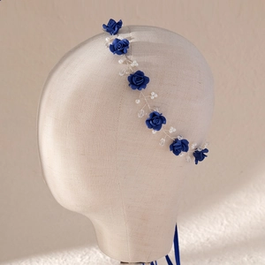 Detailed view of bridal headband with navy roses and pearls on mannequin stand