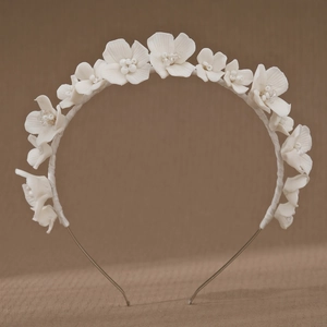 White clay flower bridal headband with handmade crystals and pearls on brown fabric
