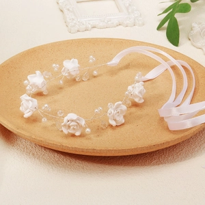 Detail of handmade white rose bridal headband with pearls and satin ribbons