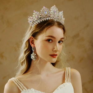 Detail view of ornate bridal silver crown and matching crystal earrings on a female model
