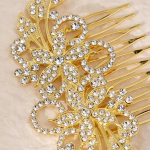 Macro shot of gold wedding hair comb featuring clear rhinestones and floral swirl design
