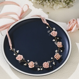 Pink handmade bridal headband with soft clay flowers and pearls on blue display tray
