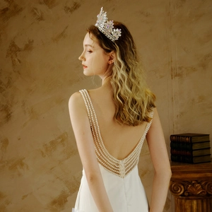 Detail shot of elegant backless wedding dress with layered pearl chains and crystal crown