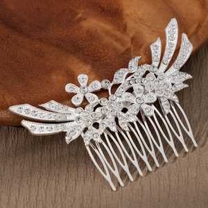 Close-up of a silver bridal hair comb with rhinestone flowers and leafy plume patterns