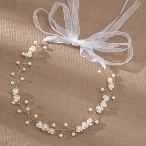 Macro-opname van handgemaakte bruidshaarband met witte bloemen, parels en een grote tule strik