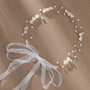 Detail van bruidshoofdband met witte 3D-bloemen en parels op zijden organza lint