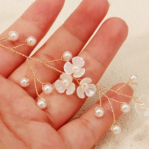 Detail van handgemaakte bruidshoofdband met gouden draden, witte bloemen en parels