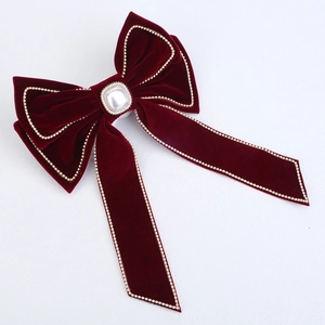 Close-up of red velvet bow hair clip with central pearl and rhinestone edges