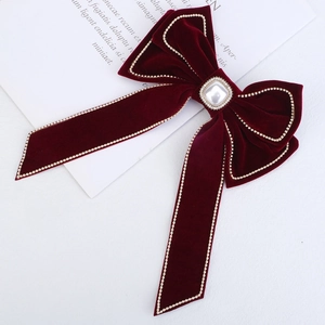 Detail of red velvet bow hair clip with a large square pearl and rhinestone centerpiece
