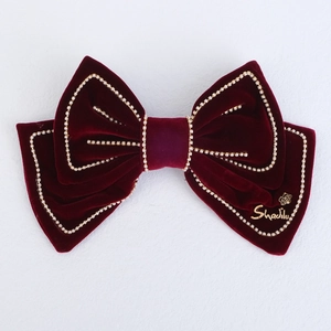 Detailed close-up of dark red velvet bow hair clip with white pearl trim decoration
