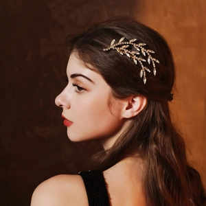 Detailed view of a vintage gold leaf bridal hair comb with sparkling rhinestones on model
