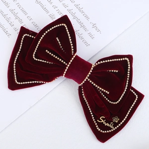 Detail of red velvet bow hair clip with gold beads and metal flower charm for women