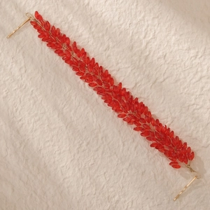 Détail de l'accessoire de cheveux mariée avec cristaux rouges et fil doré sur fond naturel