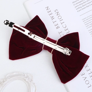 Detail view of red velvet bow hair clip with pearl chain and metal spring clip back
