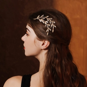 Detail of vintage leaf bridal hair comb with sparkling rhinestones on gold metal base