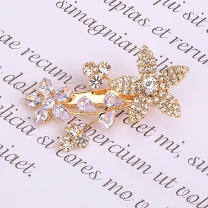 Detailaufnahme der goldenen Blumen-Haarklammer mit lila und klaren Zirkonia-Steinen