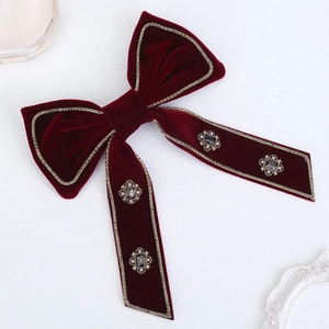 Detailed macro of burgundy velvet bow hair clip with vintage pearls and golden beads