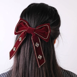 Detail of red velvet bow hair clip with gold embroidery and rhinestone accents on back of hair