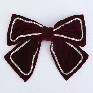 Macro detail of red velvet bow hair clip with sparkling silver rhinestone trim border