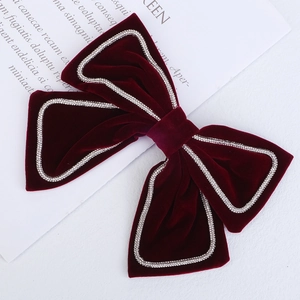 Close-up of red velvet bow hair clip with sparkling silver rhinestone trim and fabric texture